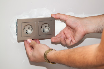 handyman removes the frame from the electrical outlet to fix the problem