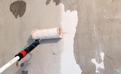 Paint roller on a concrete wall-primer, adhesive.