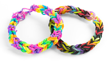 A pair of bracelets made with small rubber bands on white.