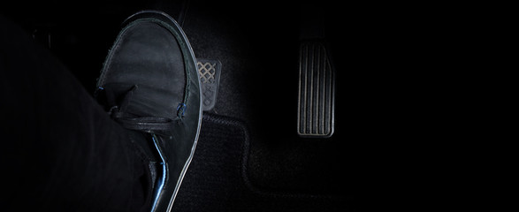 Man foot and accelerator and brake pedal inside the car or vehicle and copy space which black color...