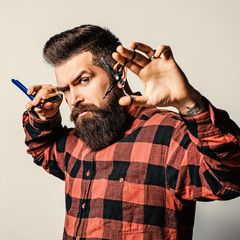 Portrait of bearded brutal barber holding razor isolated on white.