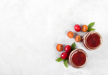 Plum jam in a glass jar on a light background top view copy space