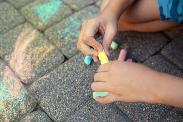 Blurred image Multi-colored colored chalk in a child's hand close-up. The concept of joy, positive, good mood and happiness. Blurred image, selective focus. No focus.