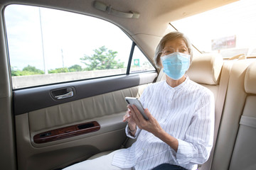 Asian elderly woman wear face mask in car or taxi prevent from covid-19 pandemic illness crisis. New normal and social distancing concept