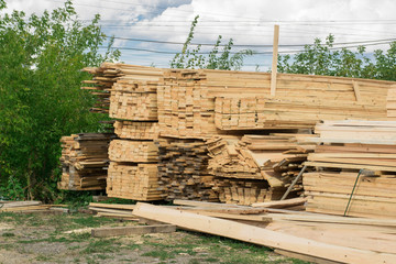 Warehouse for sawing boards on a sawmill outdoors. Industrial warehouse timber mill, many planed wooden boards.