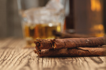 Three rolled cigarillos on wooden table close up