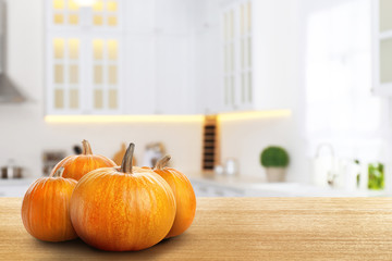 Fresh pumpkins on wooden table in kitchen. Space for text