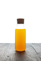 a glass bottle of fresh and cool orange juice on a table isolated on a white background
