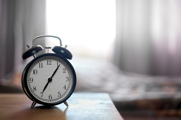 Vintage black alarm clock on bedroom. Morning time background concept with copy space.