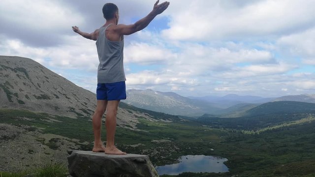 man stands on top of a mountain with open hands. at the top of the mountain, a man with his arms spread wide.