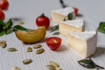 Charcuterie board of assorted cheeses, vegetables and appetizers. Above Top view table scene on a white wood background.