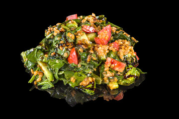Delicious fresh spinach with spelled, tomatoes and avocado with reflection,