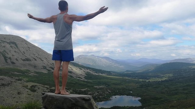 man stands on top of a mountain with open hands. at the top of the mountain, a man with his arms spread wide.