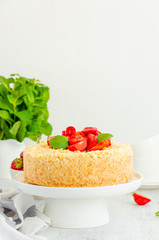 Cottage cheese grated casserole with crumb and fresh strawberries on top on a white plate on a light wooden background. Traditional Russian cake. Vertical, copy space.