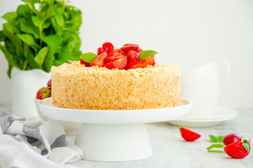 Cottage cheese grated casserole with crumb and fresh strawberries on top on a white plate on a light wooden background. Traditional Russian cake. Horizontal, copy space.
