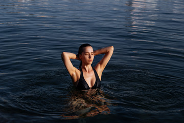 Young woman resting alone. Picture of calm relaxed girl in water swimming.Enjoy summer vacation 2020.Girl, model in the sea. The image of life, style, fashion, beauty.