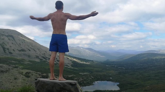 man stands on top of a mountain with open hands. at the top of the mountain, a man with his arms spread wide.