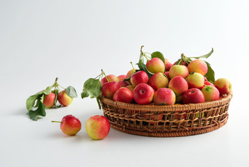 Red and yellow ripe apples with leaves close-up in a wicker basket on a light top view. No people