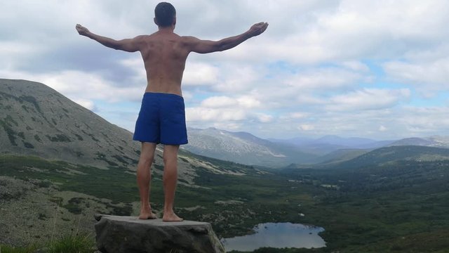 man stands on top of a mountain with open hands. at the top of the mountain, a man with his arms spread wide.