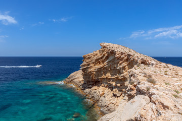 A Cape Punta Galera entering in the turquoise sea and a speedboat.  Ibiza, Balearic Islands, Spain