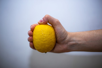 Male hand with veins holding a whole lemon, close-up