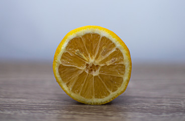 Close-up of a sliced lemon standing on a wooden table with the pulp in the lens