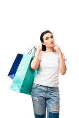selective focus of pensive and brunette woman holding shopping bags isolated on white