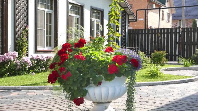 White cachepot in a flower garden with beautiful flowers and decorative plants