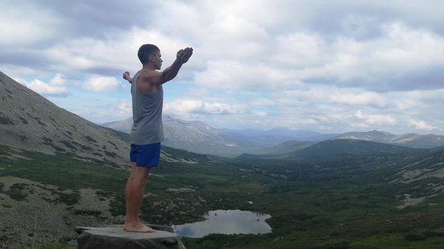 man stands on top of a mountain with open hands. at the top of the mountain, a man with his arms spread wide.