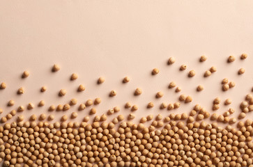 Raw chickpea seeds pile spilled over beige surface. Natural food background composition. Vegan protein source. Plant extract, nutrient-dense meal. Staple food crop. Agriculture, cultivating legumes.