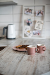 A pair of pink coffee cups. Kitchens in light colors. Morning routine, breakfast preparation. Modern interior in the style of minimalism. Hot tea with cookies. Lifestyle