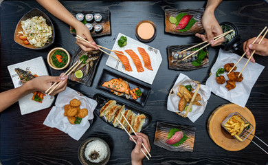 Top view of people eating Japan food on wood table together.