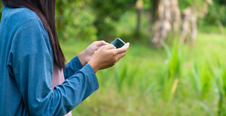 Close up of woman sending sms on cellphone in Chinese garden