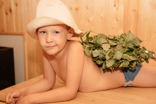 Two kids with a bucket and a basin in the sauna. Twin boys relax in the bath. Cute children in the sauna on a wooden shelf. Steam and heat in the Russian sauna.