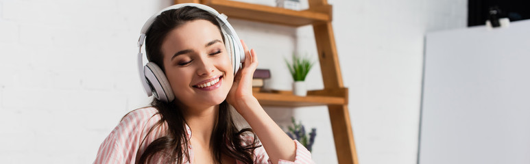 horizontal image of woman with closed eyes listening music in wireless headphones