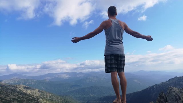 man stands on top of a mountain with open hands. at the top of the mountain, a man with his arms spread wide.
