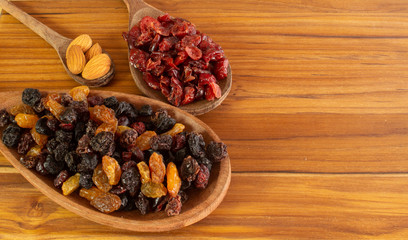 three spoons full of almonds, craberries and raisin