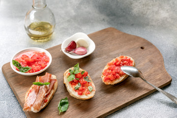 bruschetta, toast, with sliced tomatoes, jamon and Basil on a wooden cutting Board and olive oil.