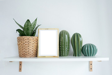 mock-up gold photo frame on a shelf with indoor flower and cacti figurines..