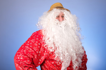 santa with a bushy beard in a summer hat looks sternly into the frame