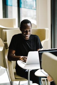 Smiling man working on laptop in cafe