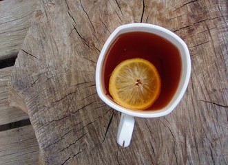 Чашка чая с лимоном на деревянном пне.