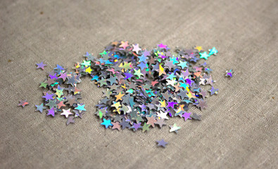 Precious sparkling colored holographic rhinestones stars on linen fabric macro closeup photo