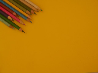 back to school with colored pencils on yellow background and coronavirus mask