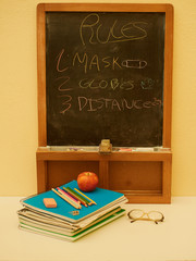 back to school with colored pencils on yellow background and coronavirus mask