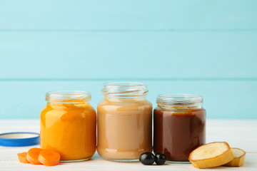 Glass jars with nutrient baby food on light background