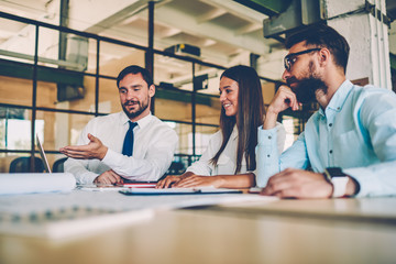 Colleagues showing to their leader online presentation of project discussing solutions, crew of employees searching information on laptop analyzing video for marketing project sitting in office