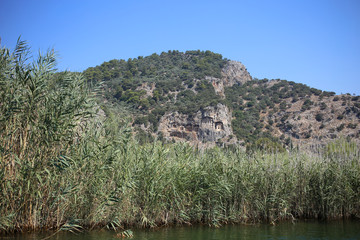 Fototapeta na wymiar Travel along the Dalyan River in Turkey, view of the rocky Lycian tombs, and high reeds.