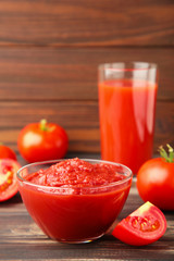 Fresh tomatoes with paste and juice on brown background