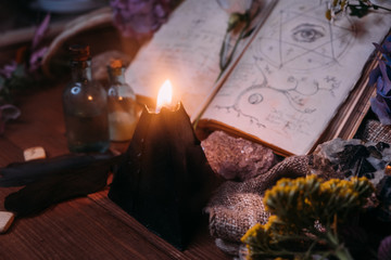 Open old book with magic spells, runes, black candle